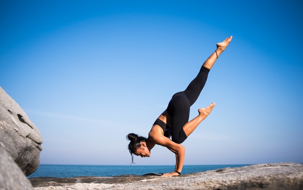 A female traveler doing yoga on a beach or in a quiet Airbnb room.